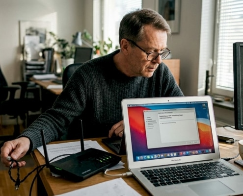 Man felsöker sitt trådlösa nätverk hemma med hjälp av dator och router.